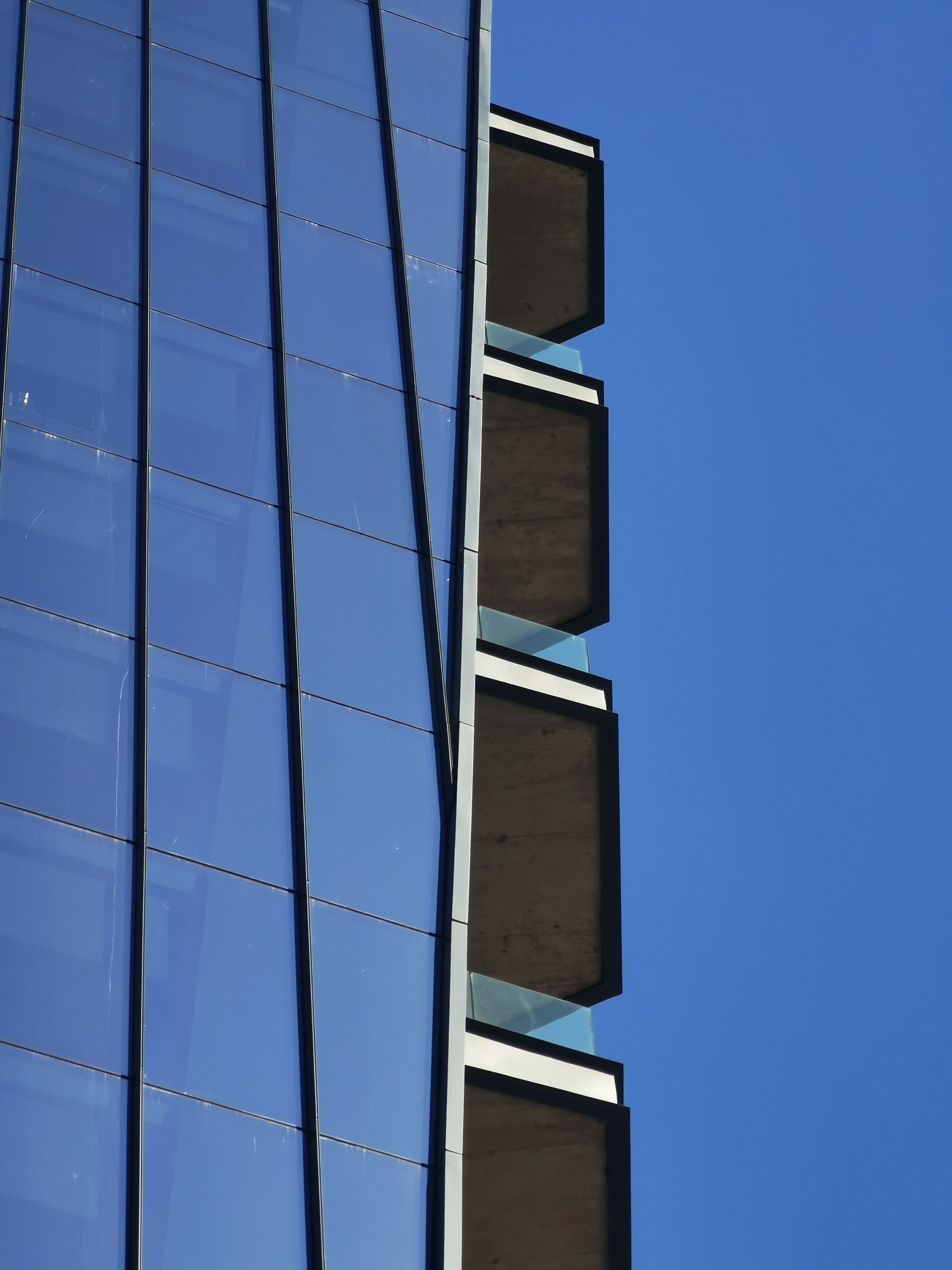 Close-up of glass skyscraper reflecting sky, showcasing urban architecture in daylight.