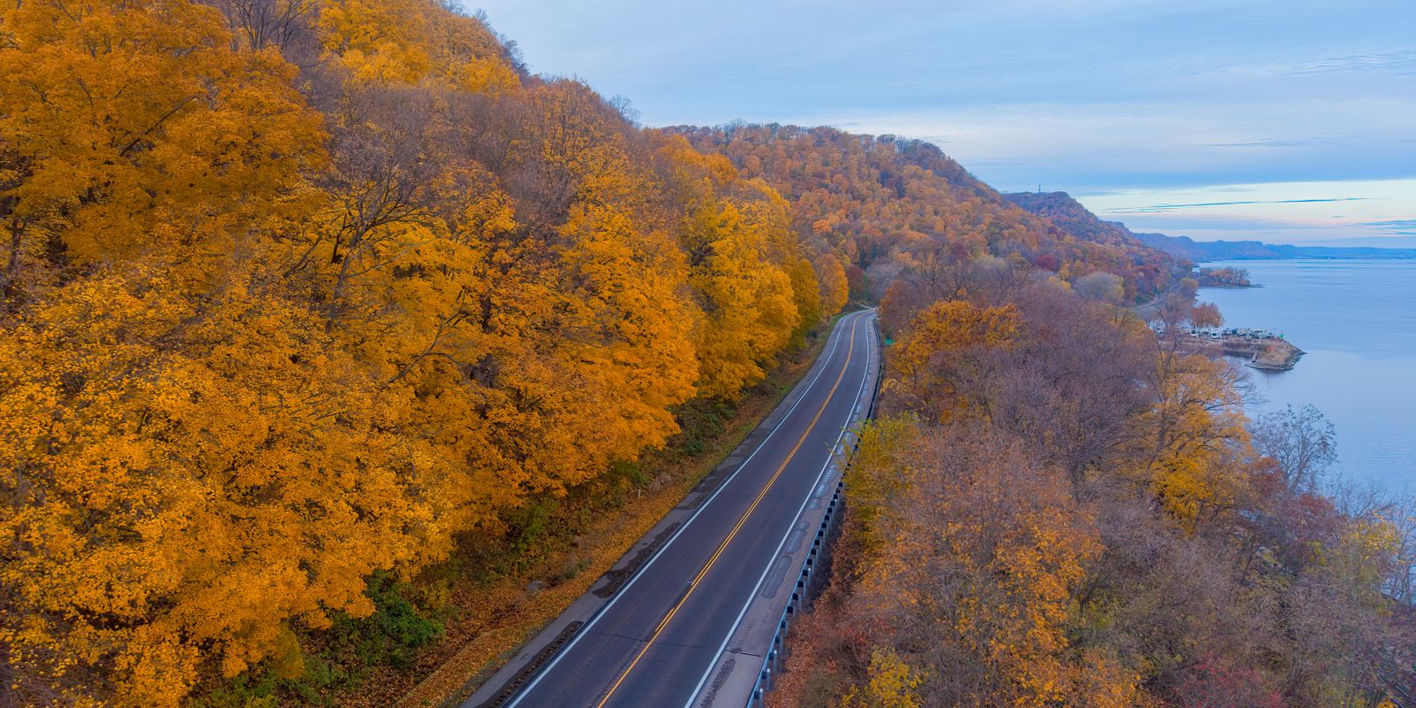 Aerial view of a winding road along a river valley in autumn