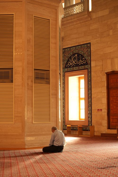 Free A man prays inside a peaceful mosque with beautiful architecture and natural light. Stock Photo