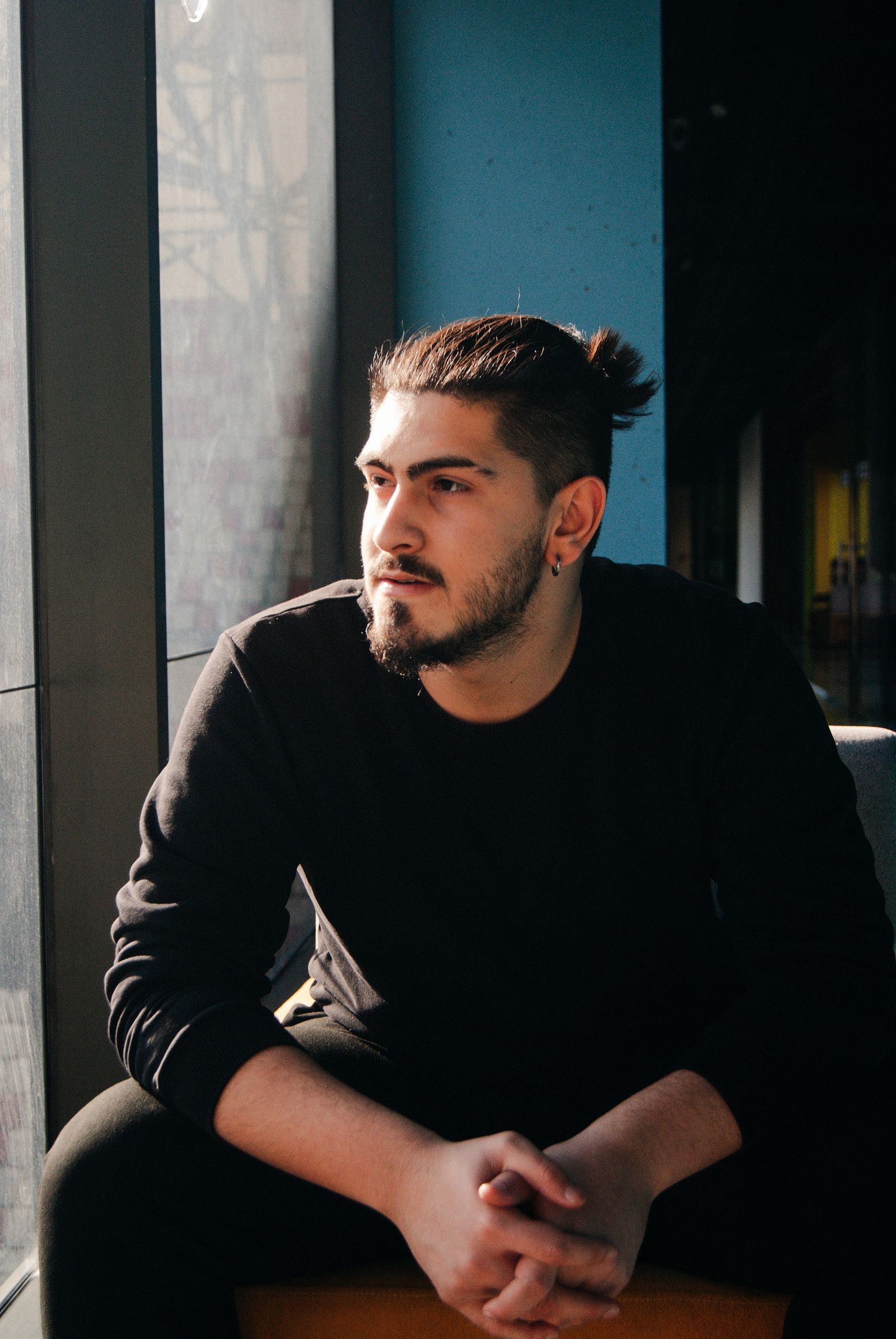 A person sitting thoughtfully beside a window