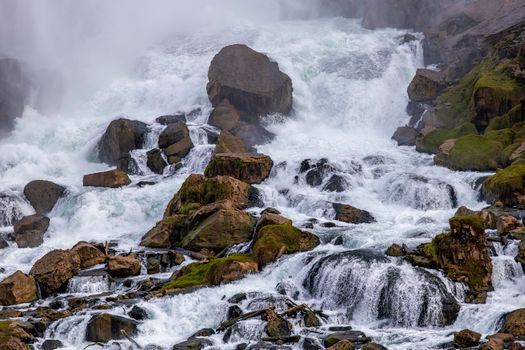 Dramatic waterfall cascading over moss-covered rocks in a natural landscape.