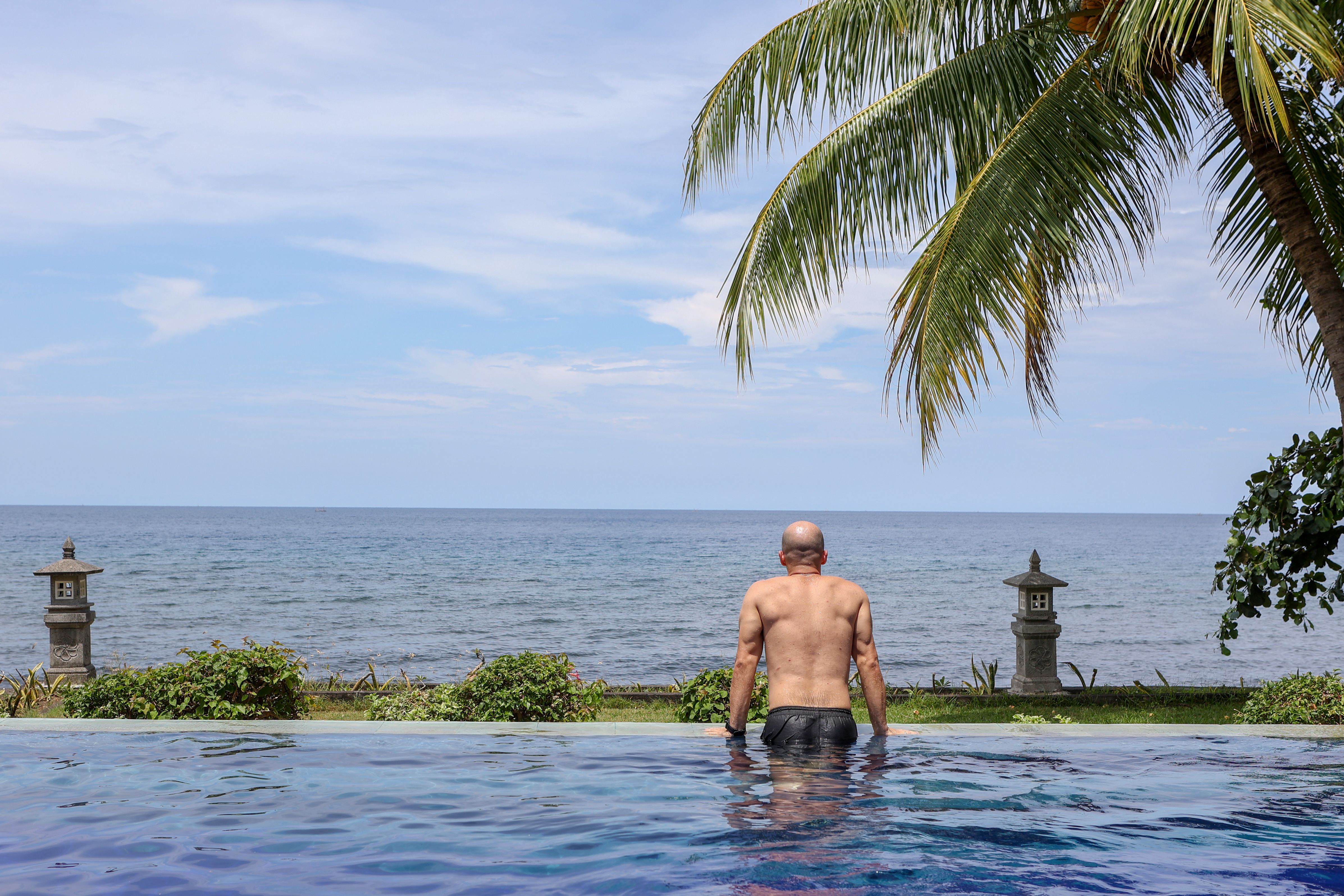 Man Relaxing in Infinity Pool by Ocean · Free Stock Photo