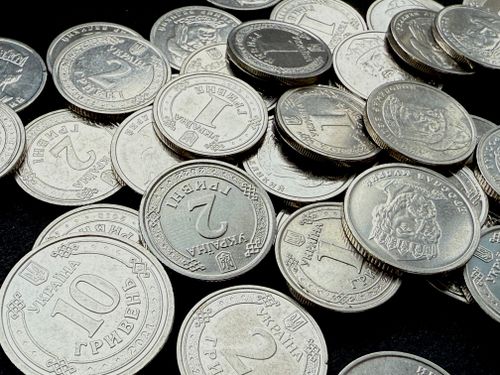 Free Close-up of Ukrainian Hryvnia coins scattered against a dark background, showing detailed engravings. Stock Photo