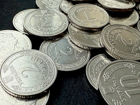 Close-up view of scattered Ukrainian coins on a dark surface.
