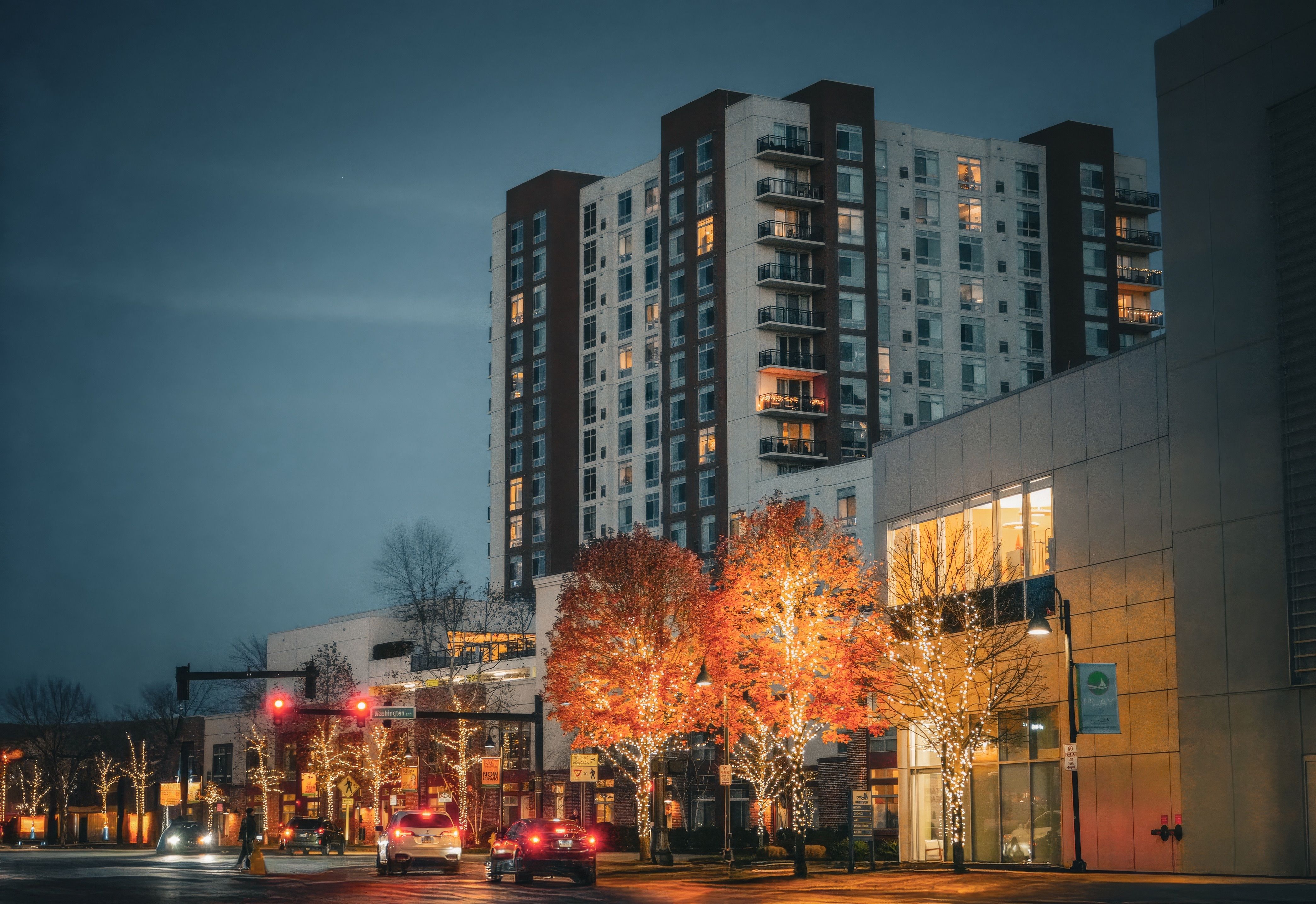 Urban high-rise building with colorful illuminated trees at twilight, enhancing the modern city vibe.