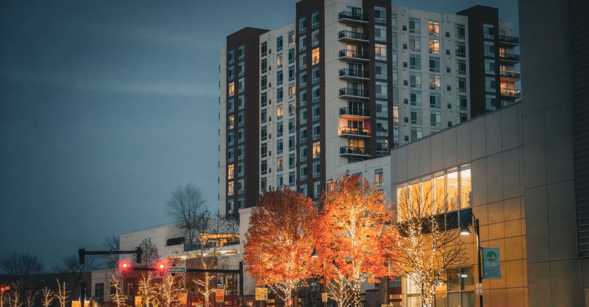 Urban high-rise building with colorful illuminated trees at twilight, enhancing the modern city vibe.