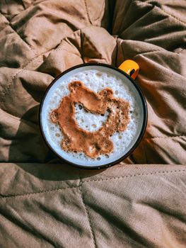 Warm morning coffee on a quilt, featuring a unique foam design for a cozy start.