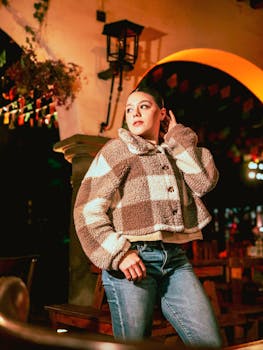 Chic night portrait of a woman in cozy fashion, vibrant urban backdrop with warm lighting.