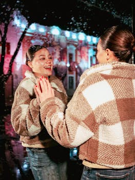 Woman admiring her reflection on a rainy urban night with vibrant city lights.