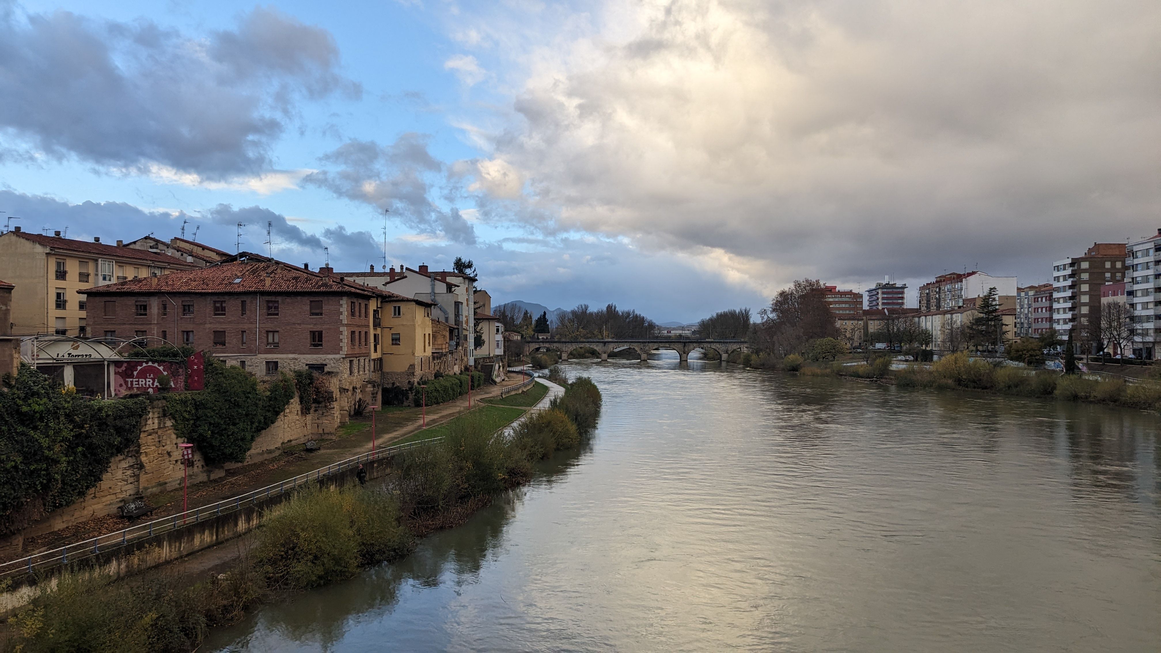 Picturesque town with historic bridge over a serene river during a cloudy day. - Logroño