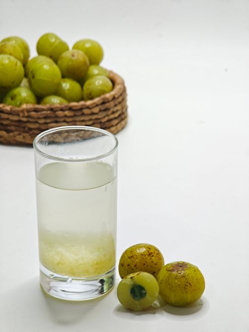 Free Glass of refreshing Indian gooseberry juice with fresh amla and a woven basket in the background. Stock Photo