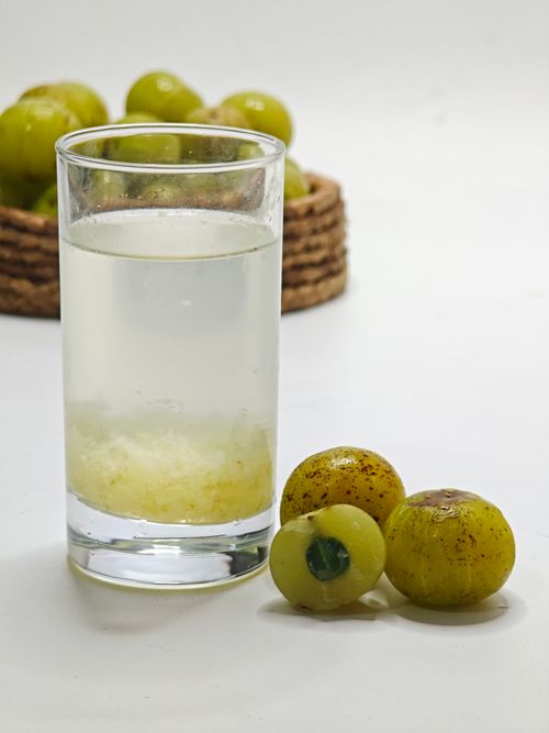 Free A glass of refreshing amla juice with fresh Indian gooseberries on a white background. Stock Photo