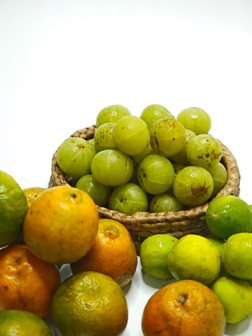 Free A vibrant display of fresh citrus fruits and Indian gooseberries in a woven basket, perfect for health and nutrition themes. Stock Photo