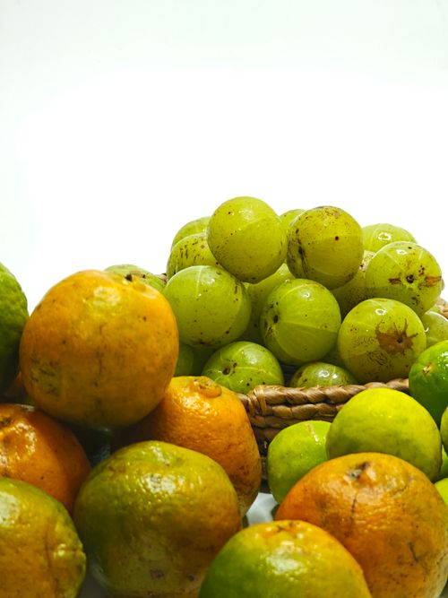Free Vibrant display of citrus fruits and Indian gooseberries in a woven basket. Stock Photo
