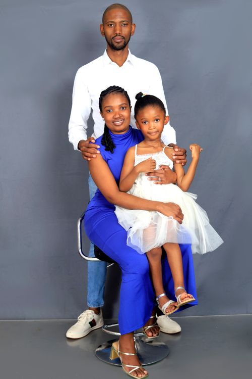 Free Stylish family portrait with parents and child against a neutral gray background. Stock Photo