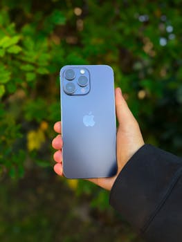 A smartphone in a person's hand with a lush green background outdoors in Istanbul.