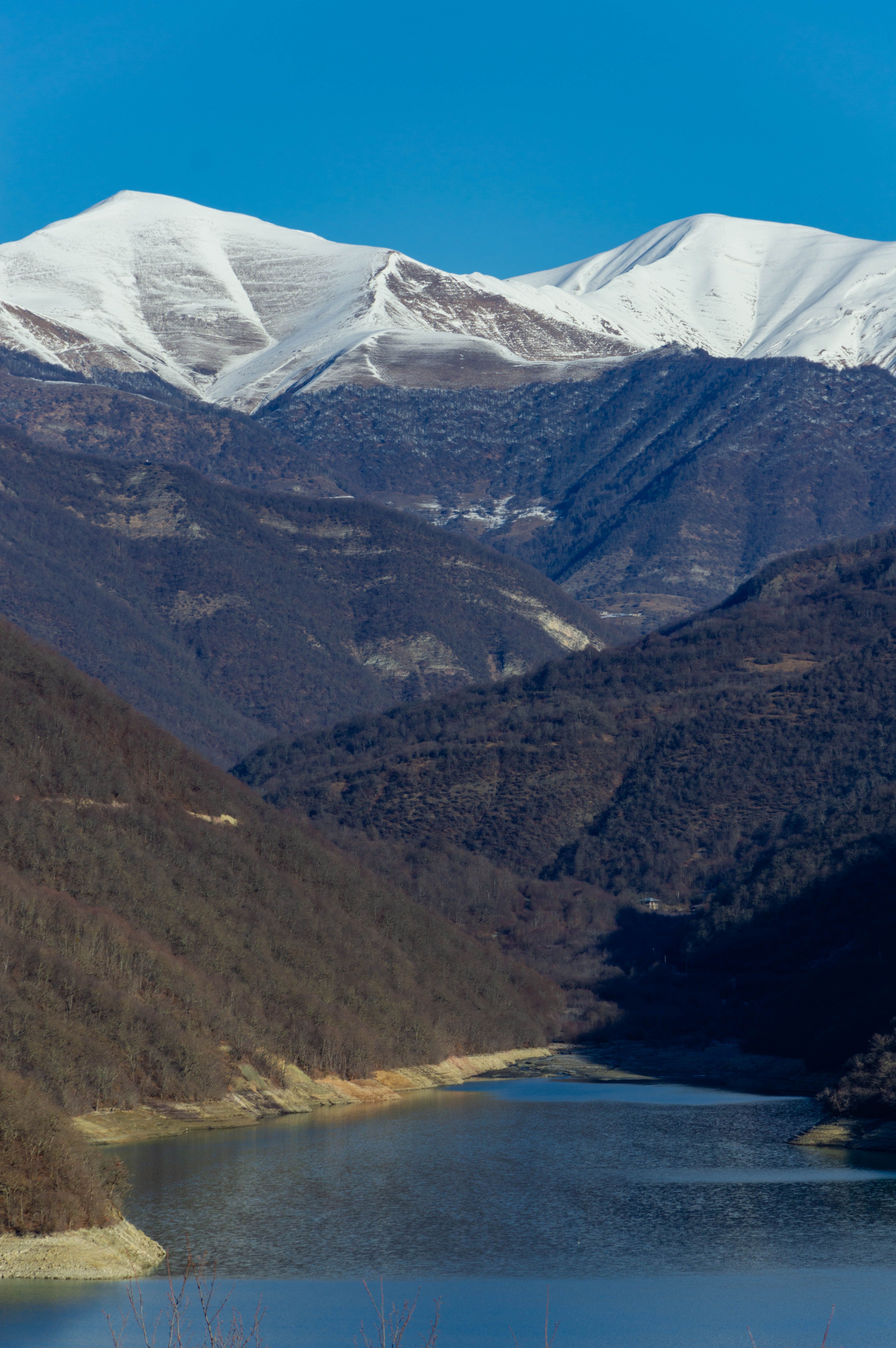 Snowy Mountains and Green Mountains Near a Body of Water · Free Stock Photo