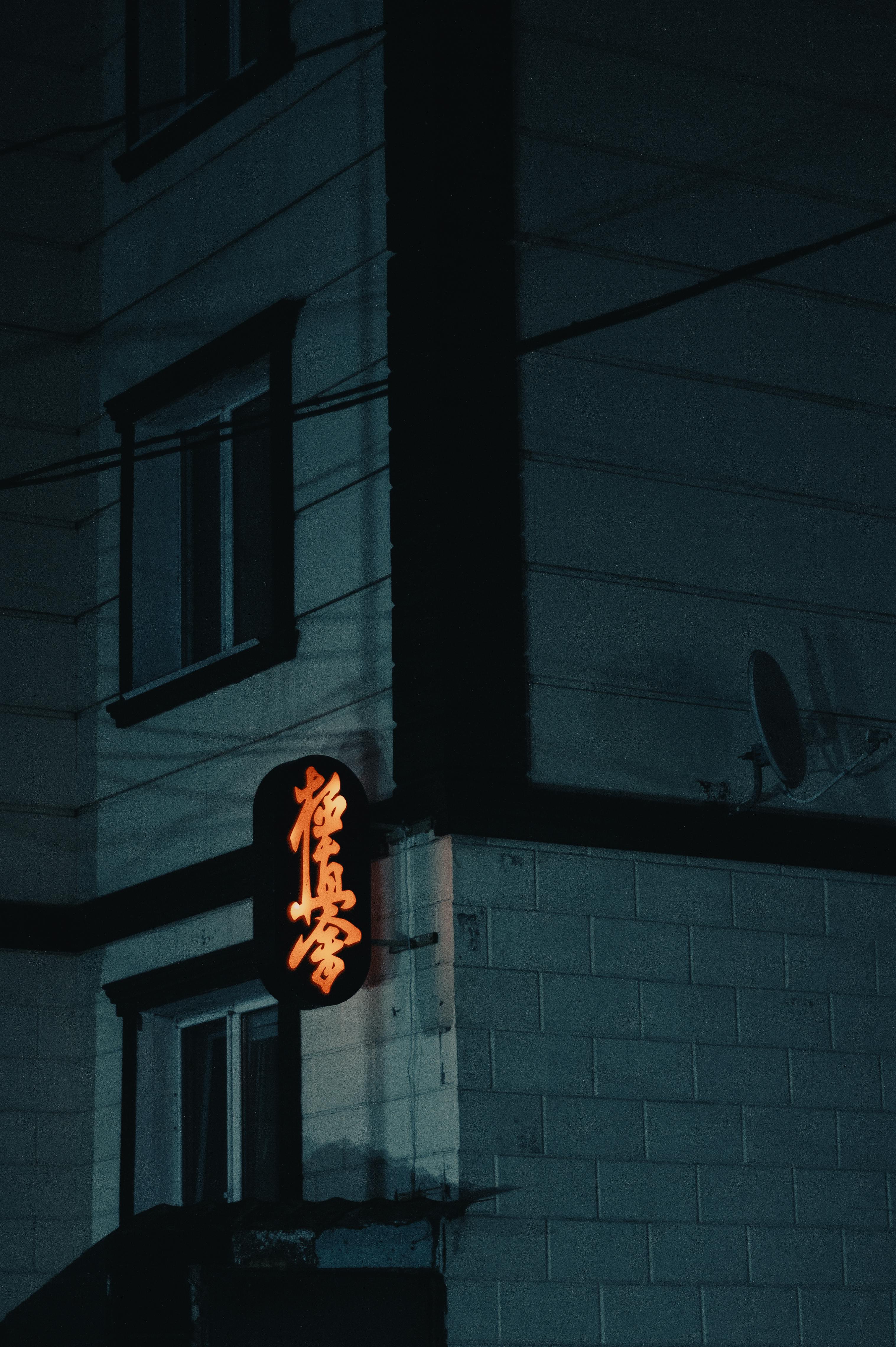 Gratuit Bâtiment urbain sombre la nuit, avec une enseigne au néon rougeoyante. Ambiance étrange et mystérieuse. Photos