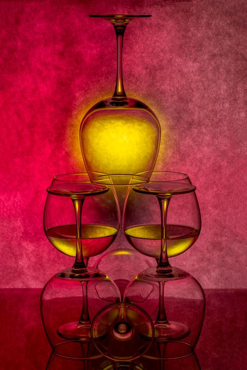 Free Upside-down wine glasses with colorful light effect on a reflective surface. Stock Photo
