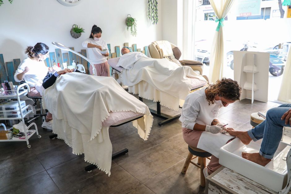 İyi aydınlatılmış bir salonda profesyonellerin yüz ve pedikür uygulamaları yaptığı huzurlu bir spa ortamı.