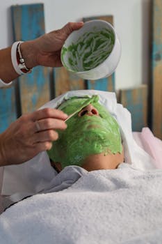A serene scene of a person receiving a relaxing green clay mask facial treatment.