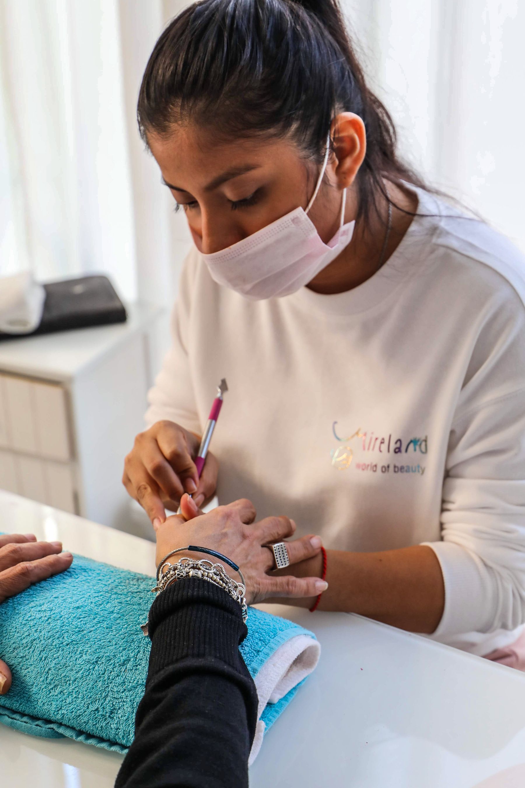 Professional nail technician applying color to a client nail