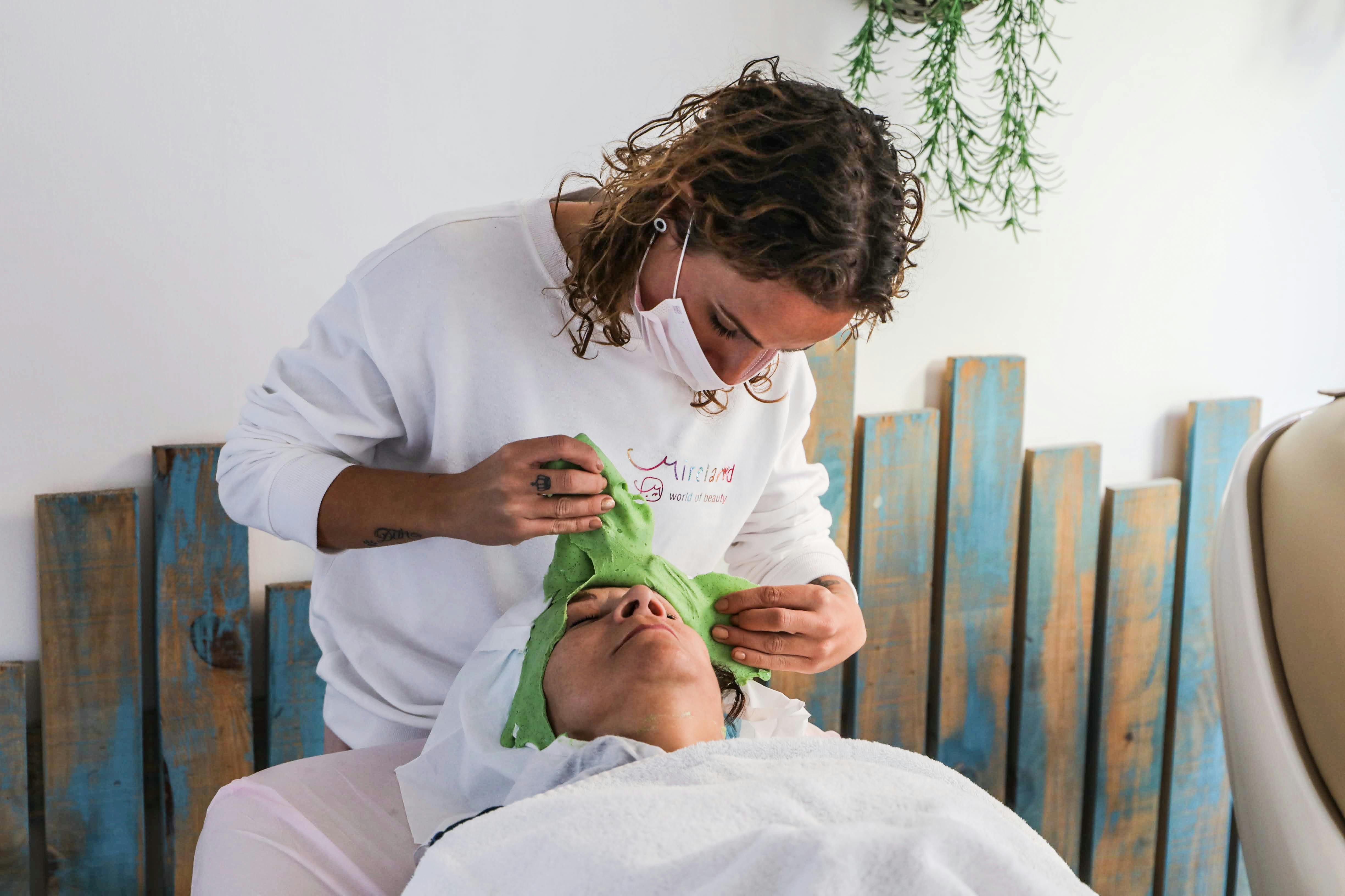 wellness spa near Long Island - A spa therapist applies a green facial mask during a relaxing spa treatment.