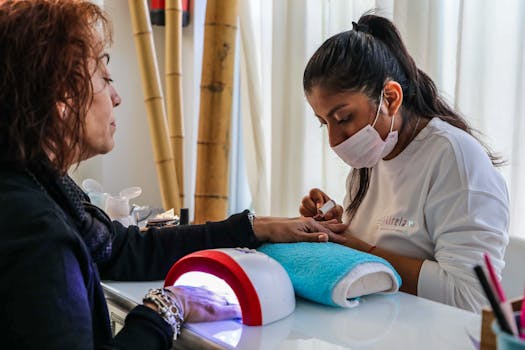 Nail technician providing a manicure service in a salon setting.