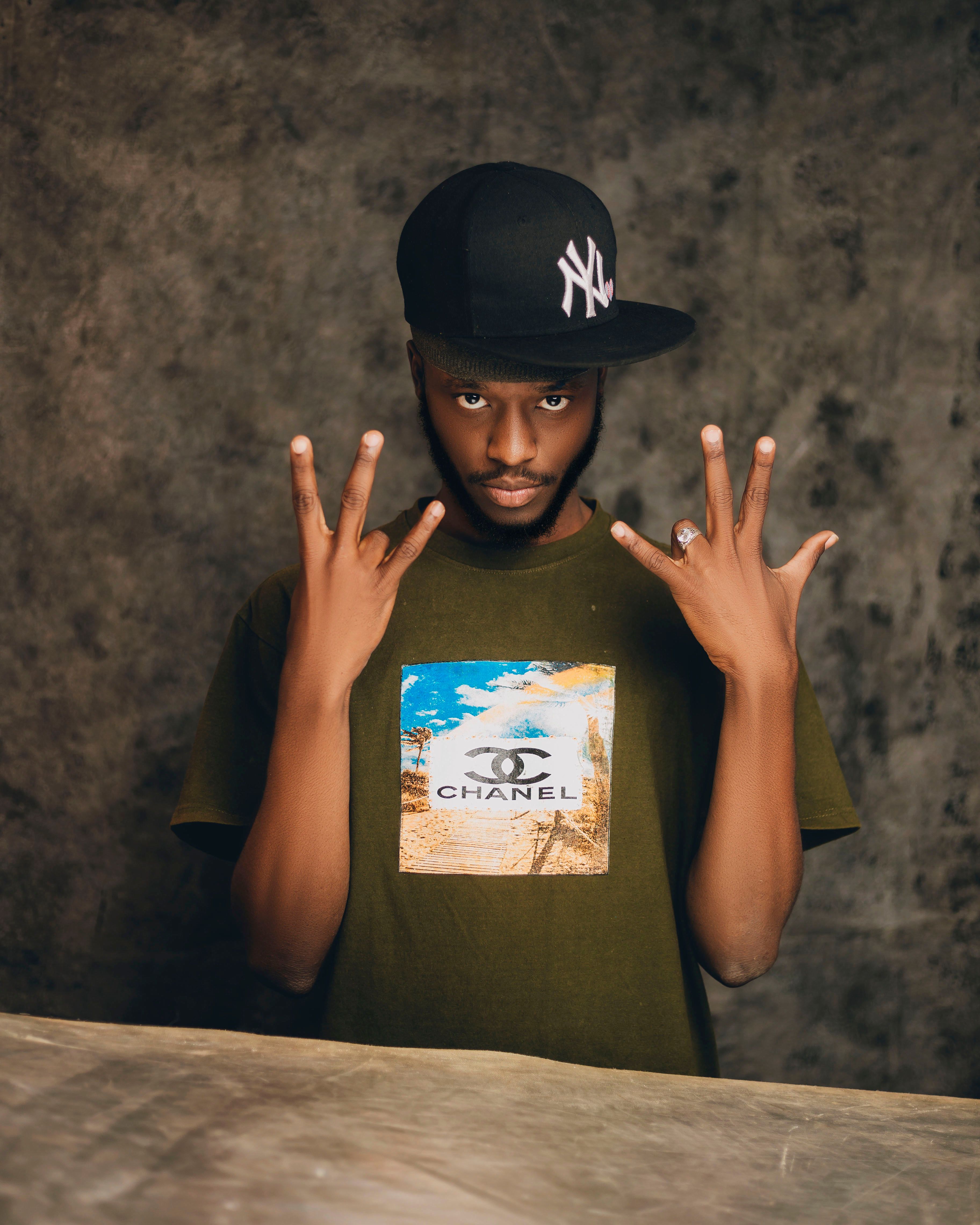 Portrait of a young man in urban fashion, wearing a graphic shirt and cap, posing confidently.