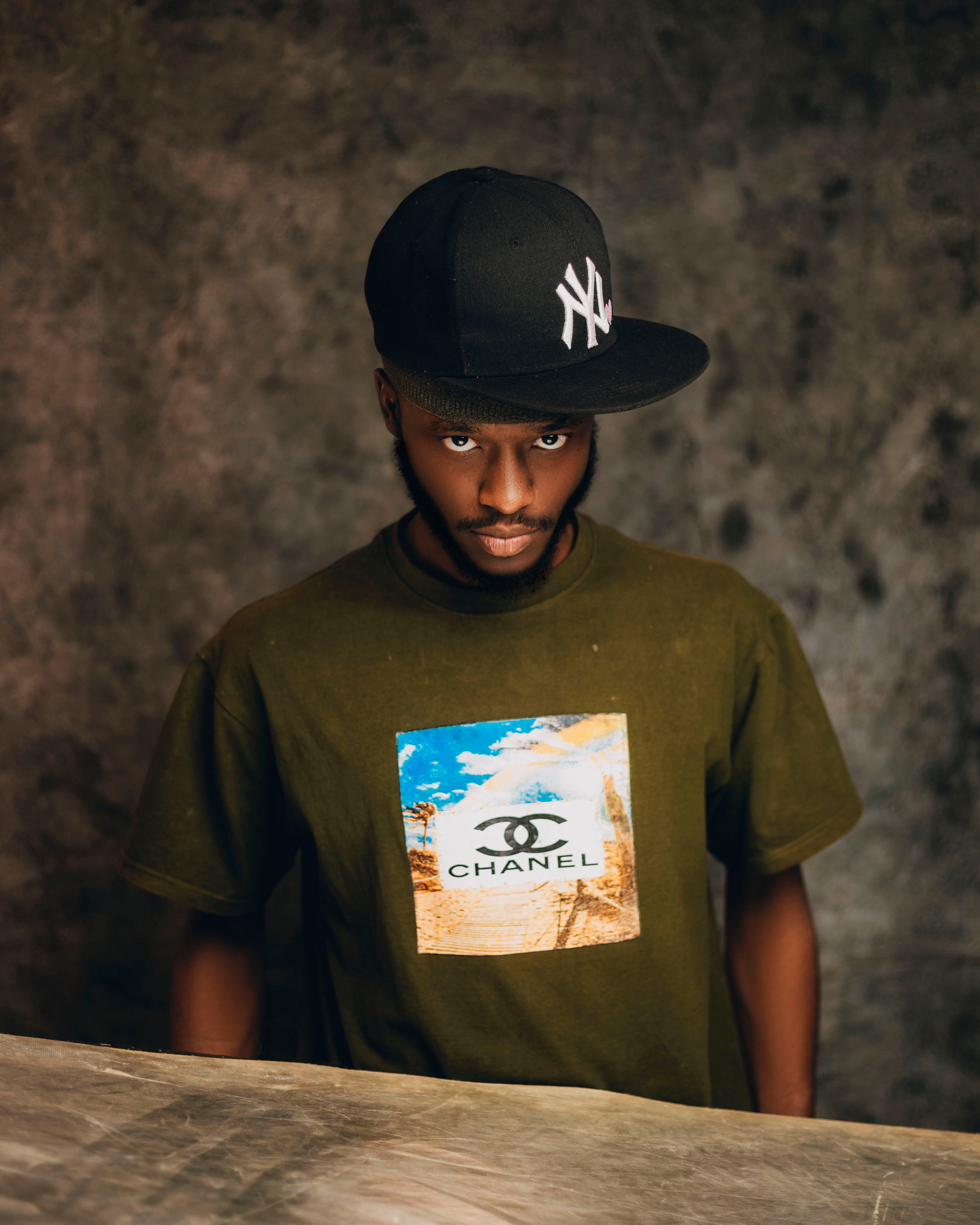 Stylish young man in cap and printed T-shirt against textured background.