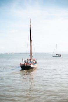 A traditional sailing boat on the Tagus River in Lisbon, Portugal, on a sunny day.