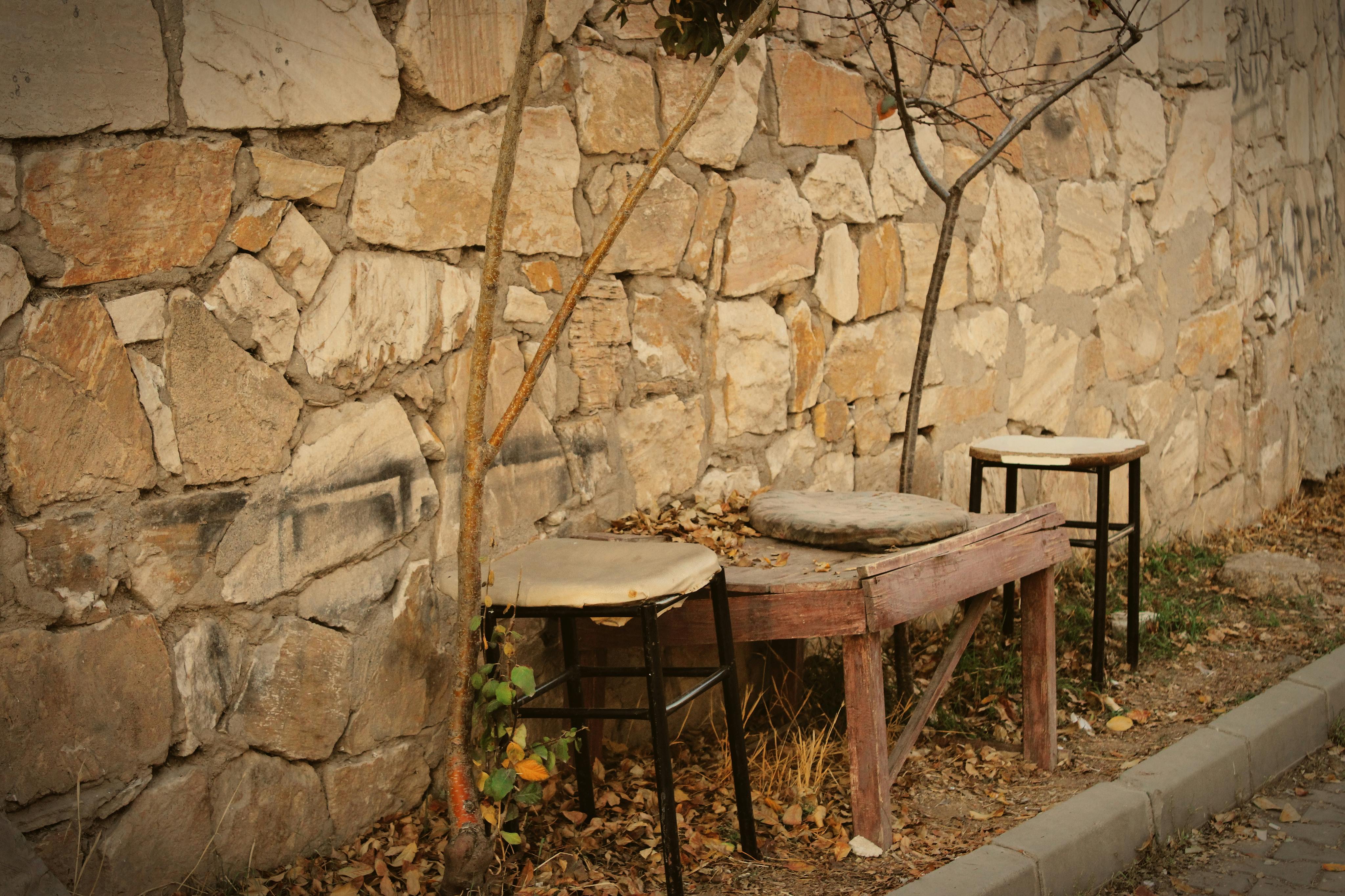 Gratuit Bănci vintage din lemn, așezate lângă un zid rustic de piatră, în aer liber. Fotografie de stoc