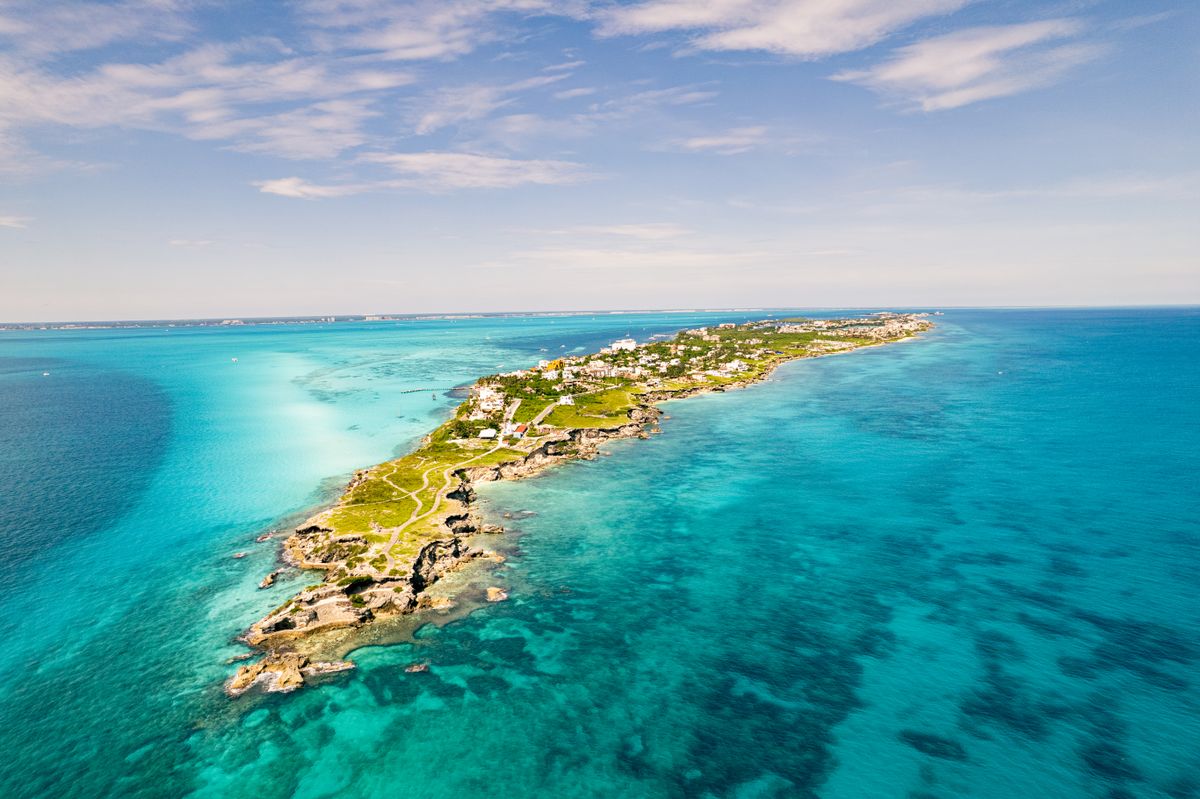 Breathtaking aerial view of Isla Mujeres, vibrant turquoise waters, and lush gre