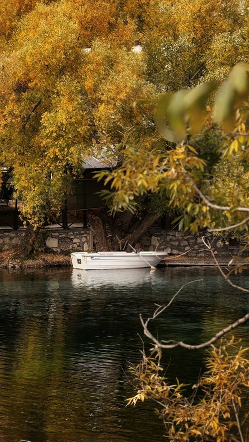 Free A serene boat floats on a calm lake surrounded by lush autumn trees in Sivas, Türkiye. Stock Photo