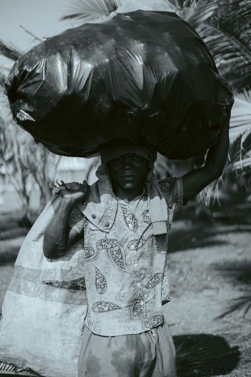 Free A man carrying a large bag outdoors, depicted in a black and white photo, showcasing traditional patterns. Stock Photo