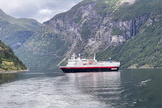 A beautiful cruise ship navigates through the stunning Norwegian fjords under a cloudy sky.