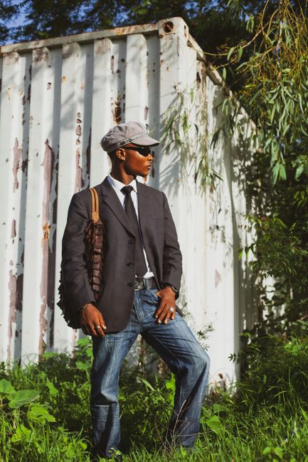 A fashionable man in a suit poses confidently outdoors in Nigeria.
