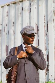 Man in a tailored jacket and cap, photo by Umar Faruq on Pexels