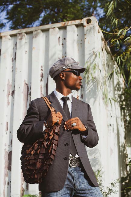 Fashionable man in sunglasses and casual suit, carrying a bag outdoors.