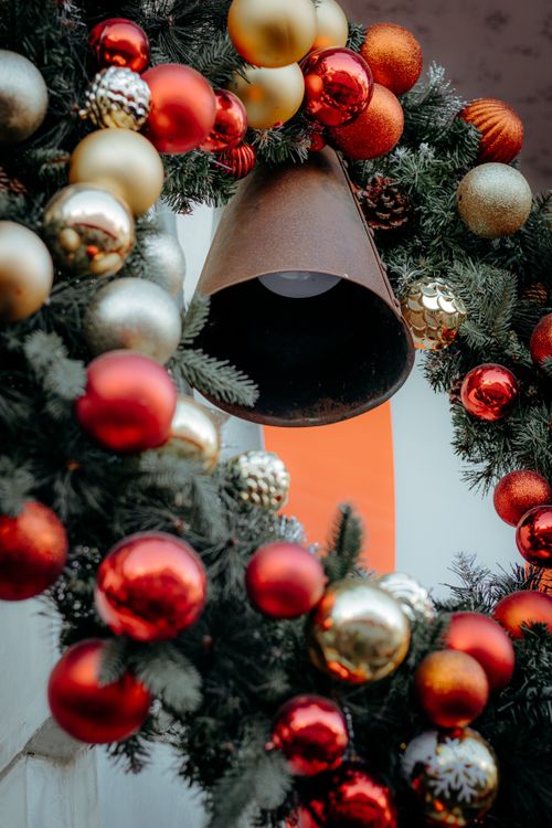 Free Close-up of a Christmas wreath adorned with red and gold ornaments, creating a festive atmosphere. Stock Photo
