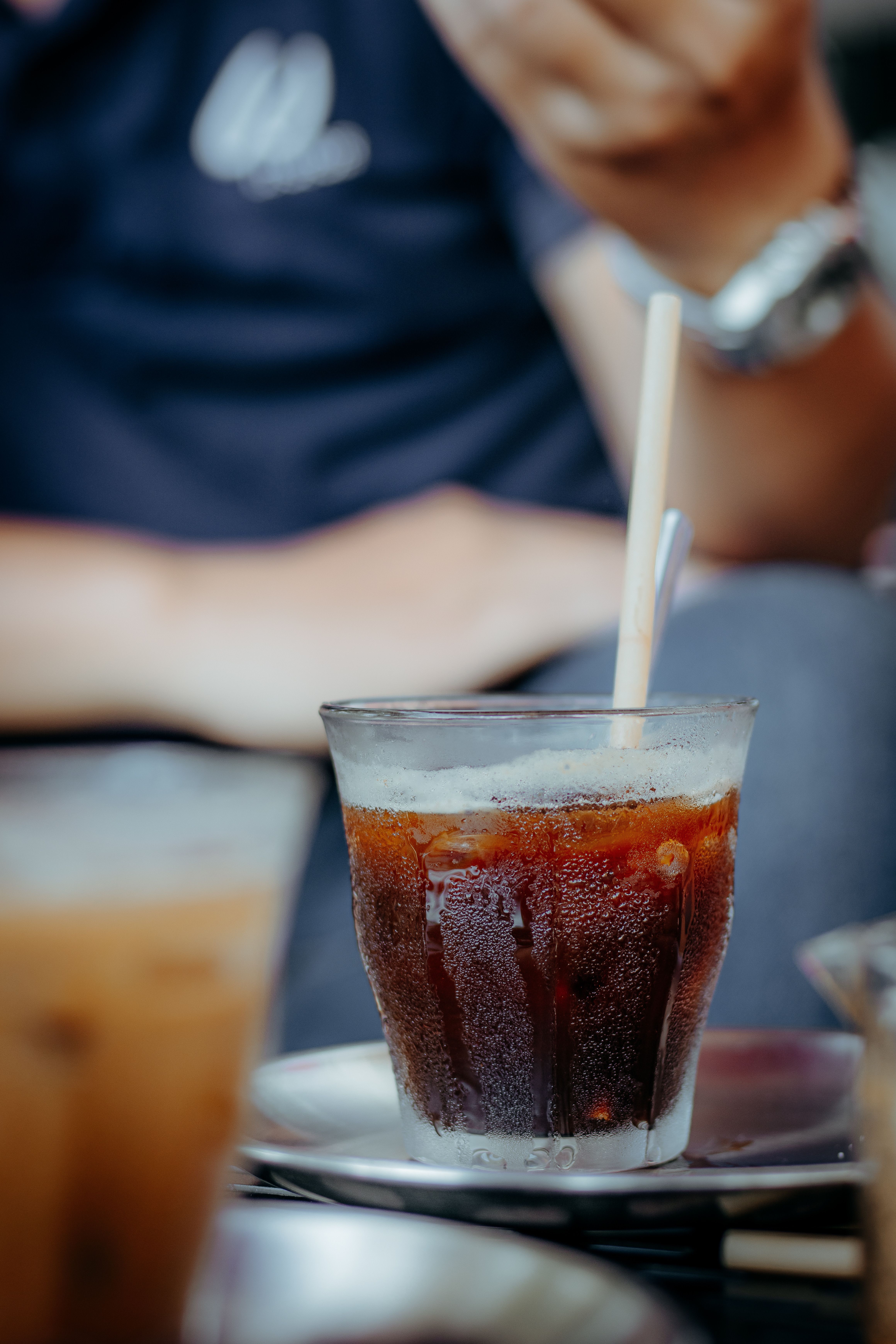 Gratis Un rinfrescante bicchiere di caffè freddo con cannuccia sul tavolino di un bar, che cattura un'atmosfera informale. Foto a disposizione