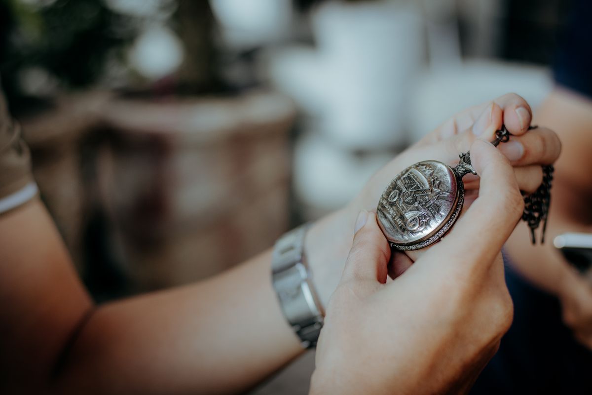 Manos sosteniendo y examinando un reloj de bolsillo antiguo