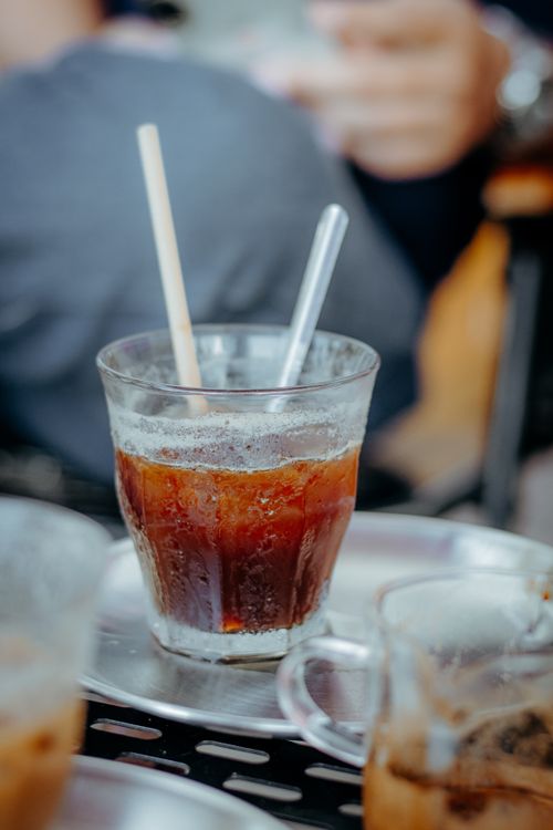 Free Close-up of a refreshing iced coffee in a glass with a straw on a metal tray. Stock Photo