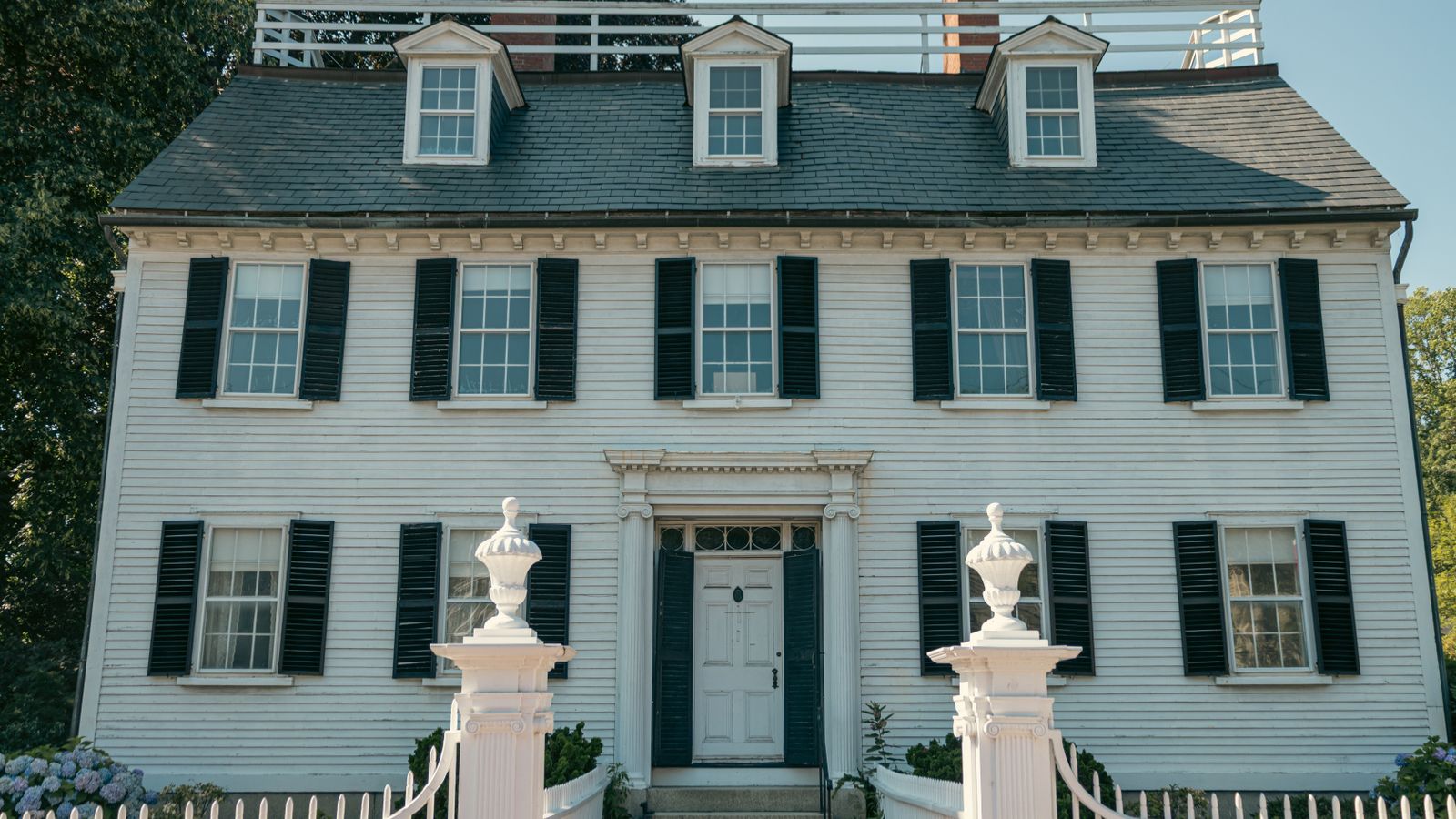 Elegant Colonial-style house with black shutters and white picket fence in Salem, Massachusetts.