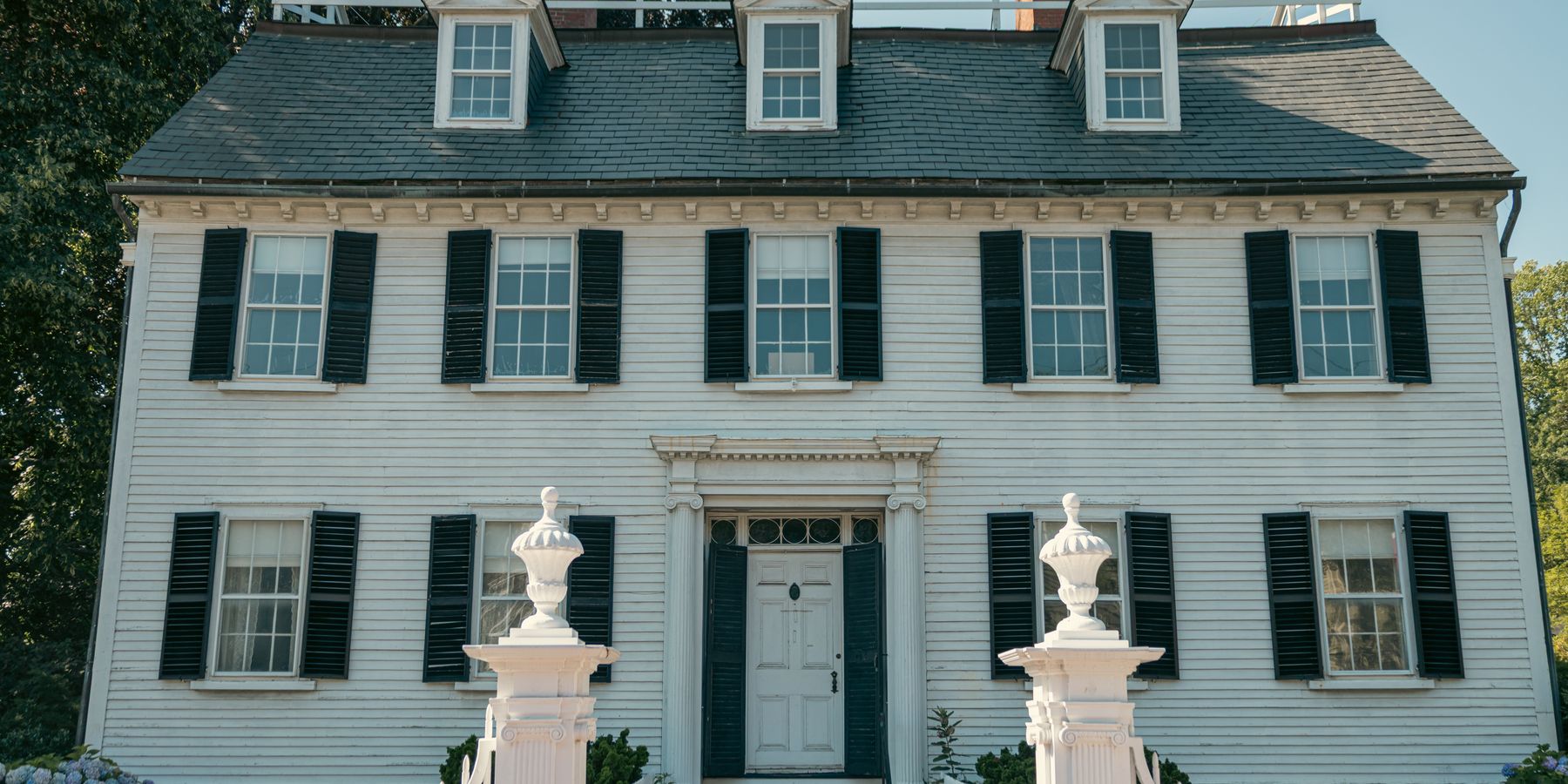 Elegant Colonial-style house with black shutters and white picket fence in Salem, Massachusetts.