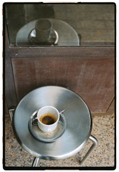 Minimalist scene of a coffee cup on a metal table, artistic view.
