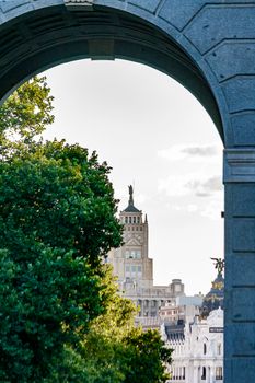Artistic shot of Telefónica Building framed by arch, captured in vibrant Madrid landscape.