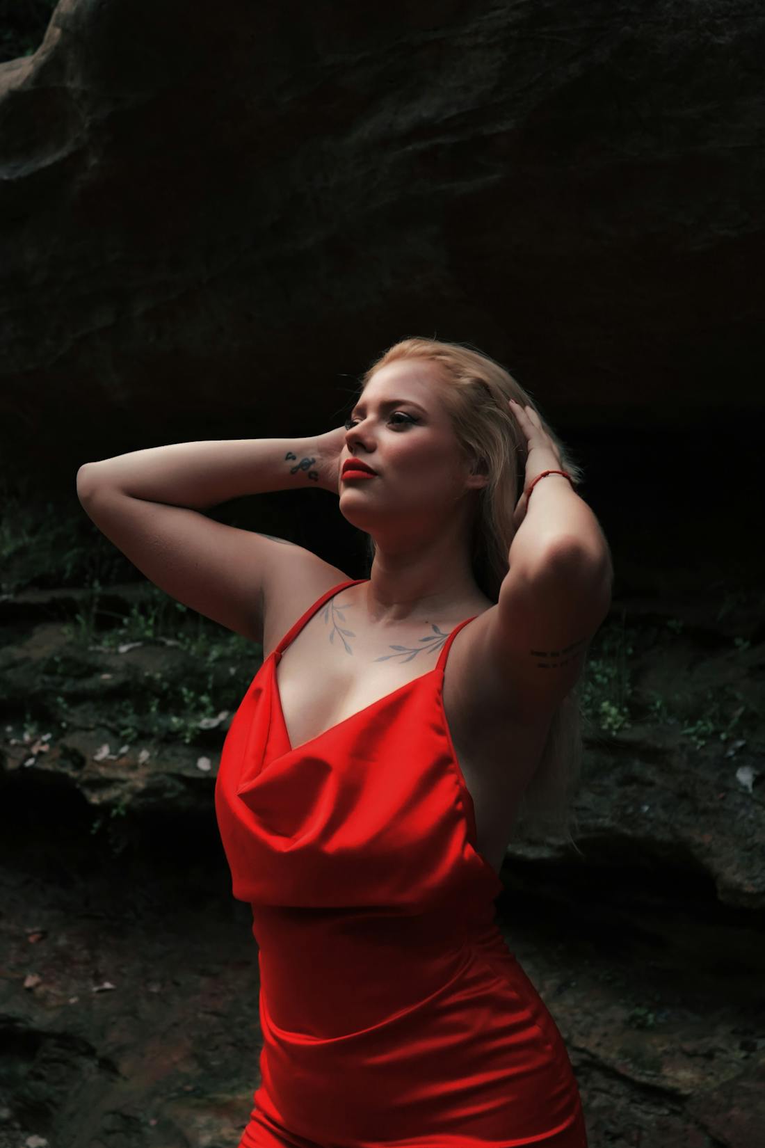 Woman in a red satin gown standing gracefully in nature