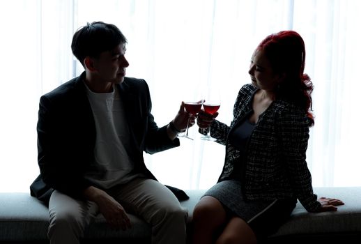 Elegant couple toasting wine indoors against a bright, stylish backdrop in Jakarta.