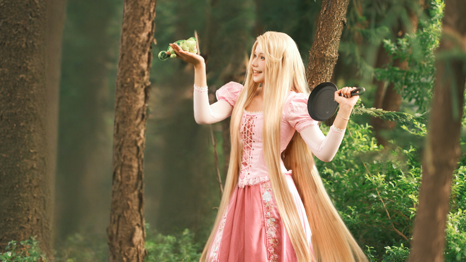 Cosplayer dressed as a fairy tale character in a lush green forest.